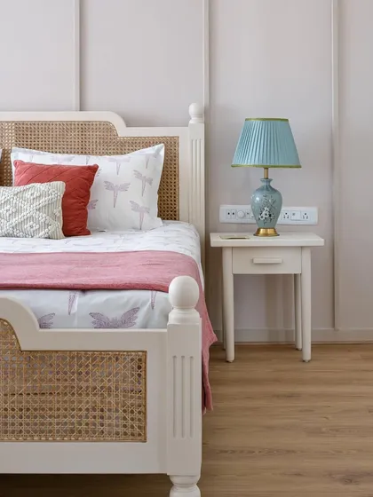 A close-up of the French-inspired bed in the 'House of Kismish' project, featuring a classic design with turned legs and cane weaving on the headboard and footboard.