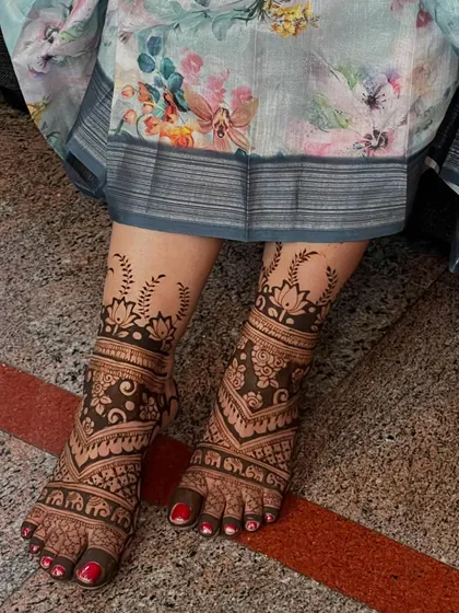 A full-coverage bridal foot design with intricate patterns and leafy motifs extending up the leg.