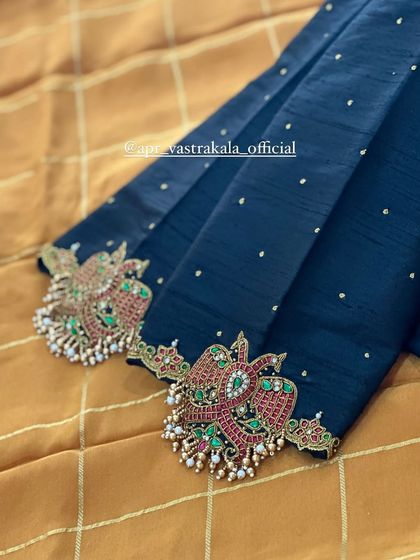 Peacock motifs crafted with kemp stones on the sleeves of a deep blue blouse.