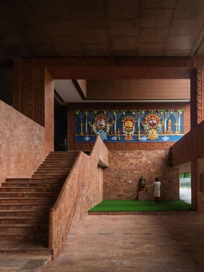 The entrance hall is a grand, double-height space with a monumental staircase and a large Pattachitra mural celebrating local culture.