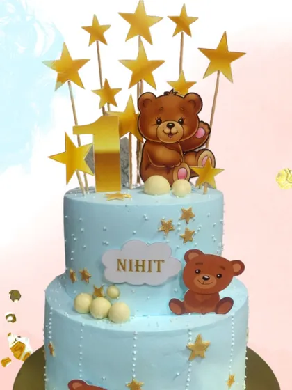 A classic and adorable teddy bear theme for a first birthday. This two-tier cake in soft blue is decorated with cute bears and golden stars, creating a sweet and memorable cake for such a special milestone.