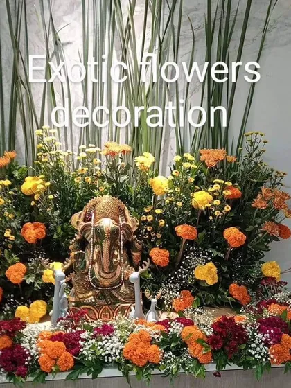 A charming Ganpati idol placed within a garden-like arrangement of colorful marigolds and tall foliage. This naturalistic design brings the beauty of an outdoor garden into your home for the festival.