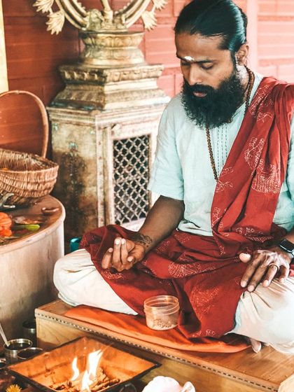 I sit in front of the sacred fire, preparing for a puja. This is a time for me to center myself and hold the space for the students, ensuring the ceremony is conducted with pure intention and devotion.
