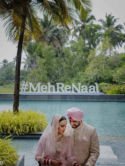 Together is a wonderful place to be, especially in Goa. The couple poses by the pool with their custom wedding hashtag, a perfect blend of modern style and the lush, tropical beauty of their destination wedding venue.