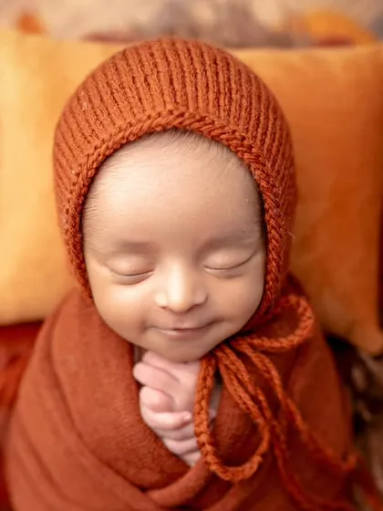 A sweet, smiling newborn in our autumn-themed setup. The warm colors and that happy expression are a perfect match.