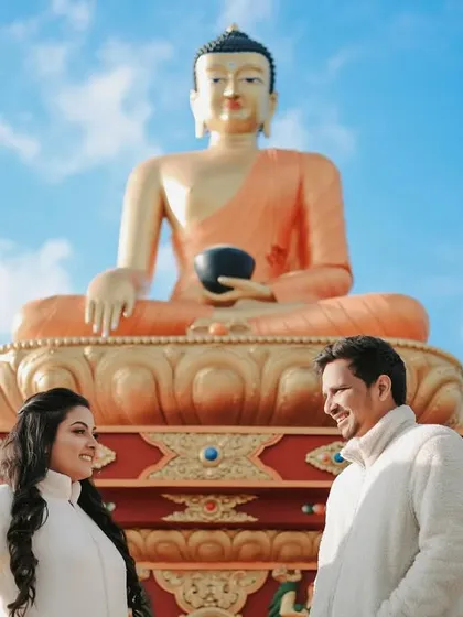 A serene shot of the couple in front of a large Buddha statue in Mussoorie. This location provides a peaceful and spiritual vibe to the pre-wedding album.