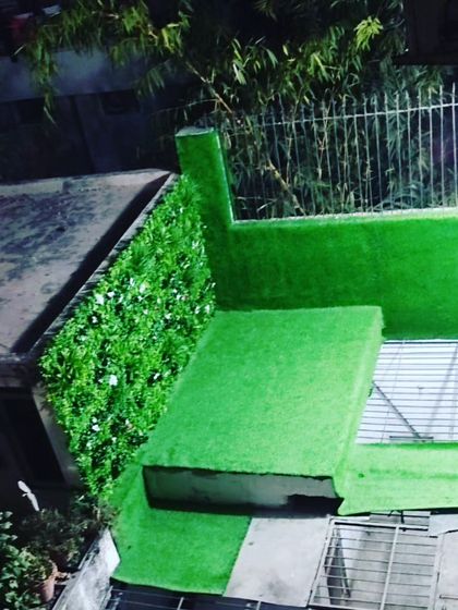 A small rooftop corner transformed with artificial grass and a short green wall. This is a simple way to make an unused space feel like a small private garden.