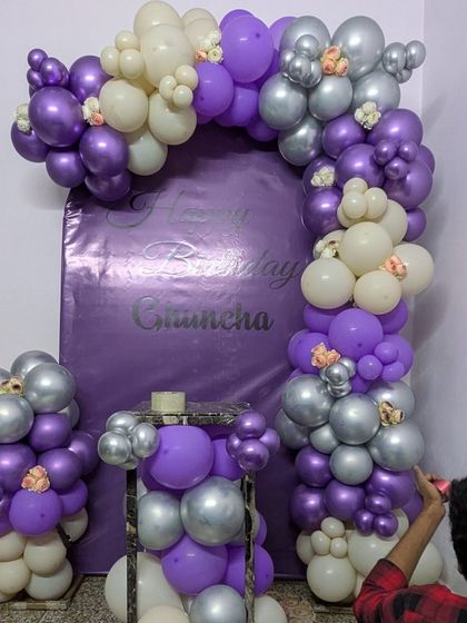 My team member adding the final touches to the purple balloon arch, ensuring every detail is perfect.