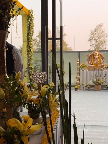 A view of the outdoor ceremony space, featuring a beautifully decorated idol of Lord Ganesha to bless the union, styled with yellow flowers to match the indoor theme.