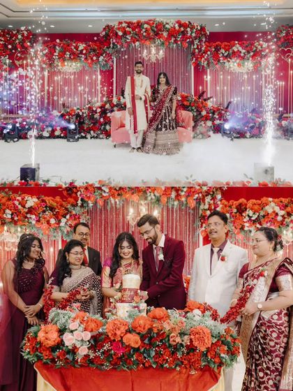 The key moments of a reception, beautifully framed. The couple's portrait on the grand stage with cold pyros and the family-centric cake cutting ceremony show a perfect blend of spectacle and intimacy.