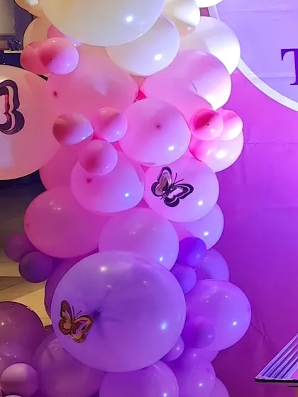 Butterfly-printed balloons mixed into the garland add an extra layer of theme to the decoration.