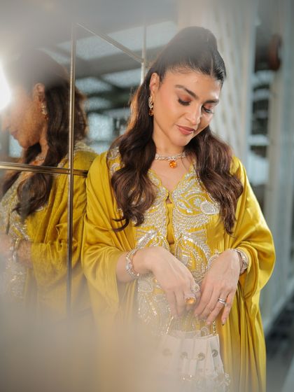 A candid, reflective moment. The soft lighting highlights the beautiful, glowing finish of her makeup.