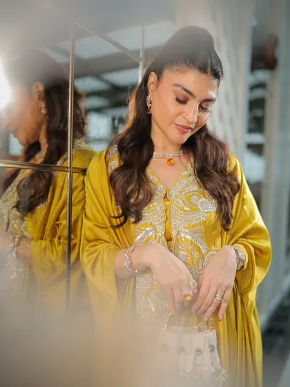 A candid, reflective moment. The soft lighting highlights the beautiful, glowing finish of her makeup.
