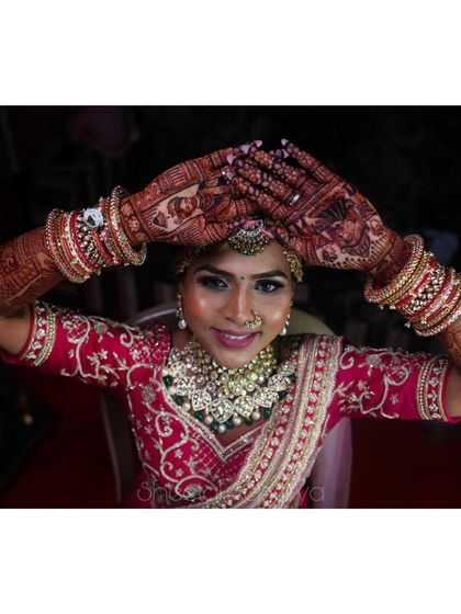 A happy bride showing off her full bridal mehendi. The design includes portraits and intricate patterns, a perfect reflection of her joy.
