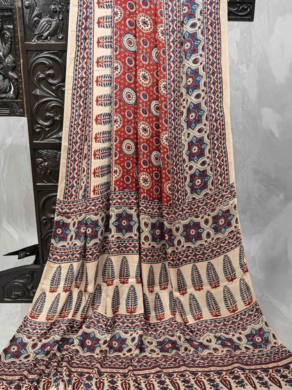 A beautiful cream-colored saree with red and blue block prints. The combination of colors and patterns gives it a classic, timeless appeal.