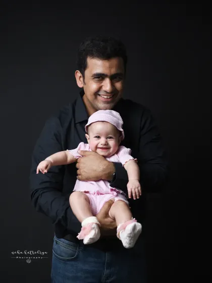 A proud father holding his smiling baby girl. This is a simple, classic portrait that beautifully captures the joy of fatherhood.