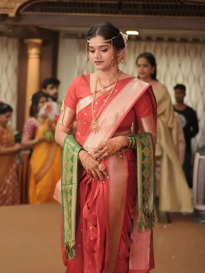 The bride's graceful entry. This full-length shot captures the elegance of her walk and the beautiful drape of her traditional red saree.