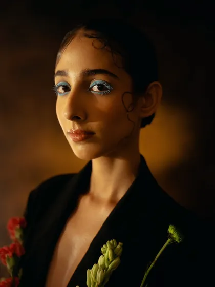 A close-up beauty shot from the same series, highlighting the pop of blue eyeliner. The play of light and shadow across her face adds dimension and artistry.