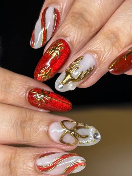 A luxurious Christmas nail art set. This design features a rich red and white base with intricate 3D gold elements, including reindeer, bows, and elegant swirls.