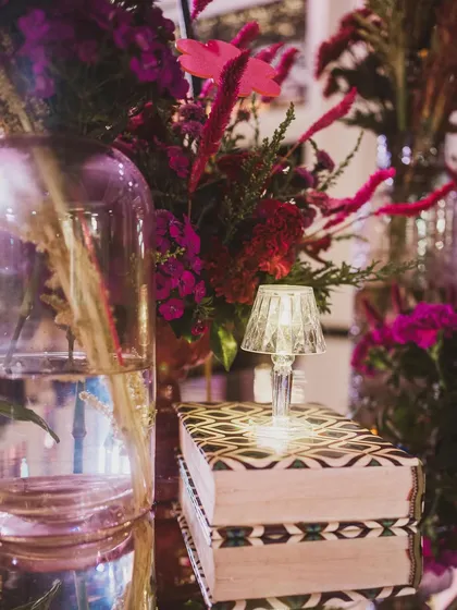 A tiny crystal lamp placed on a stack of beautifully patterned books adds a touch of whimsy and sophistication to this floral arrangement.