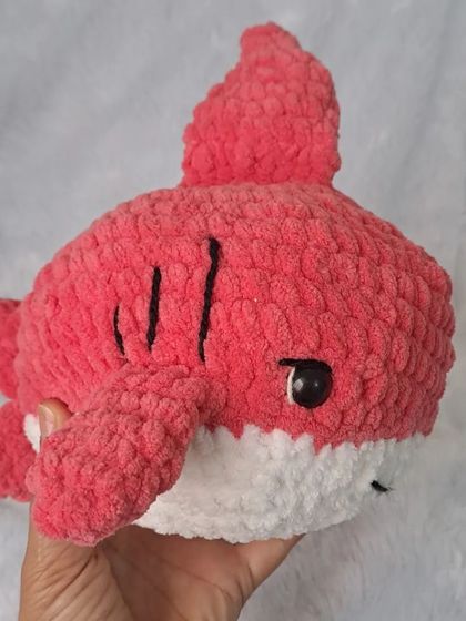 Holding the plush shark to show its soft, chunky texture.