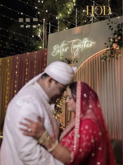 A romantic photo booth with a "Better Together" sign, set against a backdrop of soft drapes and a beautiful pastel floral arch.