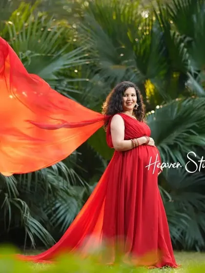 The flowing red fabric of her gown catches the light beautifully in this outdoor portrait, creating a sense of movement and life.
