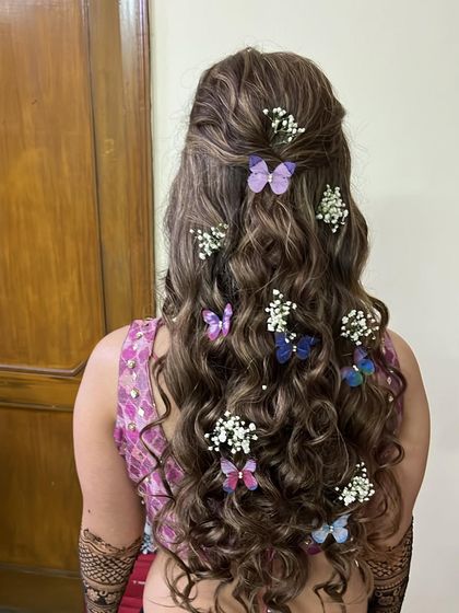 Mehendi hair goals. We love adding fun accessories like these butterflies to soft curls for a look that is festive and unique.