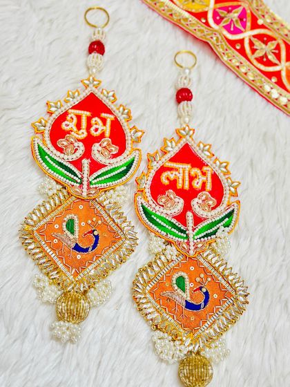 This latkan set features a lotus bud design in red and orange. The intricate beadwork and peacock details make it a beautiful symbol of purity and prosperity.
