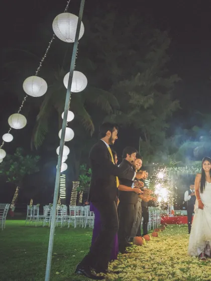 A magical reception entrance with guests holding sparklers, lighting the way for the bride under a canopy of paper lanterns.