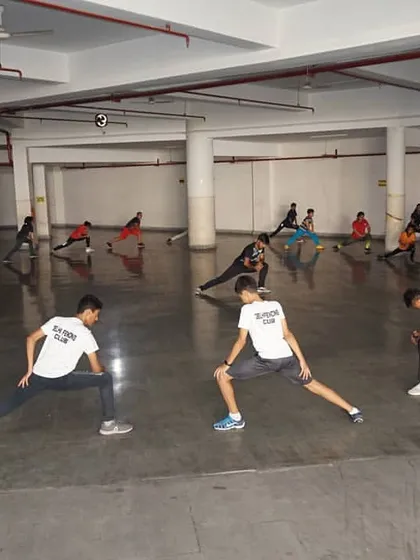 A full class of fencers participates in stretching exercises. Flexibility and proper warm ups are a critical part of our training regimen to maximize performance and prevent injuries.