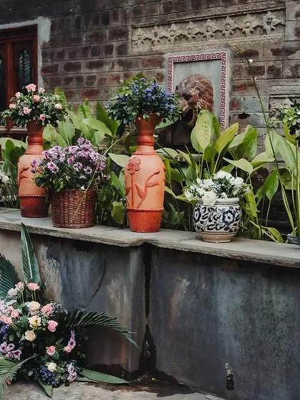 A collection of potted flowers and floral arrangements, adding color and life to a stone ledge.