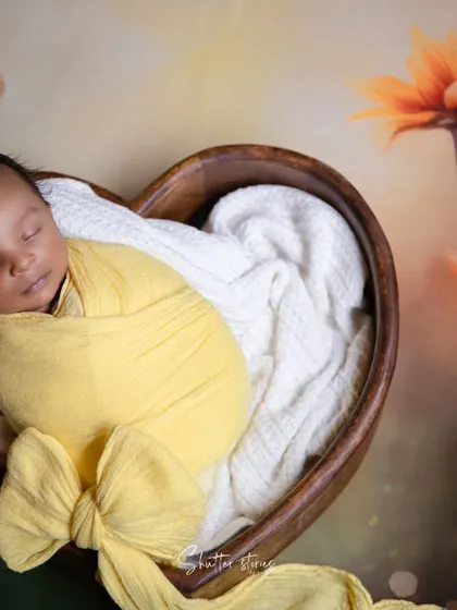 A closer crop of the sunflower theme, focusing on the baby and the large bow of the yellow wrap.