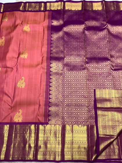 A peach-pink Kanchipuram handwoven silk saree with golden elephant motifs and a purple zari border.