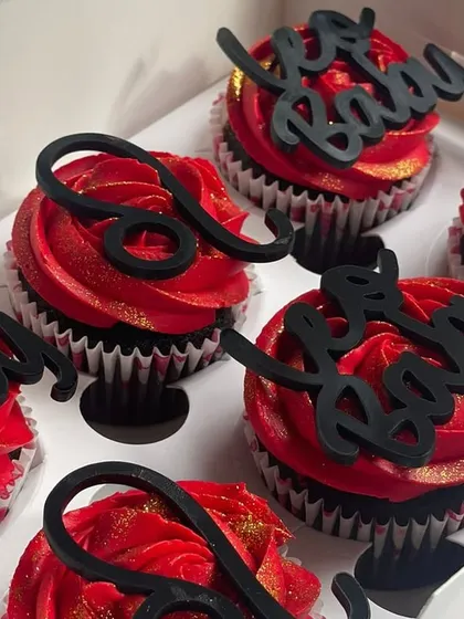 A three-quarter view of the Leo cupcakes, highlighting the height of the buttercream swirls and how the black toppers stand out against the red.