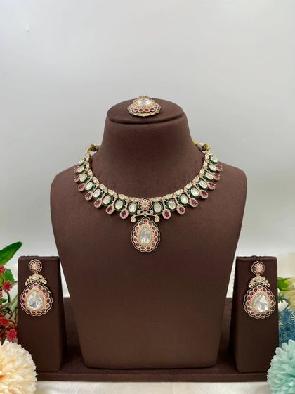 The Amaya Premium Moissanite Kundan Necklace. This set is distinguished by its large central pendant and matching earrings, featuring fine Meenakari work. It is available with red or green accents.