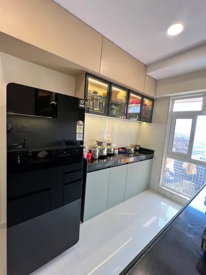 The other side of the parallel kitchen, featuring a large refrigerator and glass-fronted upper cabinets for displaying crockery.
