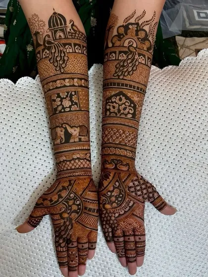 A full-arm design packed with traditional elements. It includes peacocks, elephants, and architectural domes, creating a rich and dense pattern.