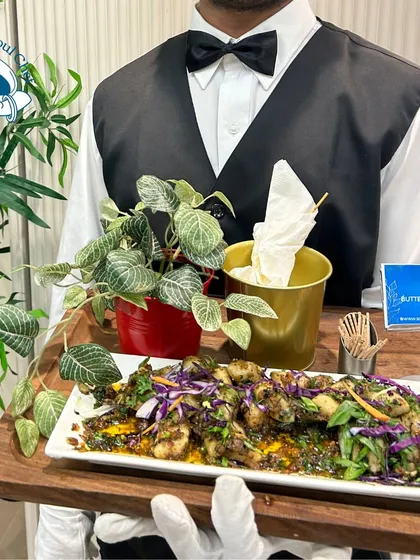 My service staff presenting a platter of Butter Lime Gnocchi. Dressed in a crisp uniform with a bow tie, he represents the professionalism and elegance that my team brings to every boardroom dinner and executive event.