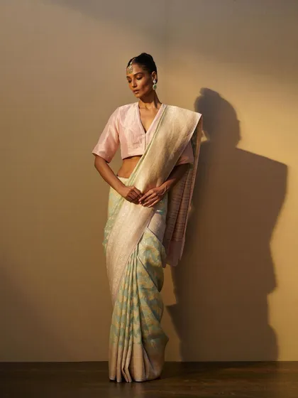 A delicate pastel blue and cream saree paired with a pink blouse. The styling is soft and feminine, highlighting the beautiful weave of the fabric.