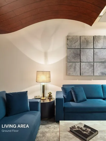 A home’s character is often found in its contrasts. Here, we paired a bold blue sofa with a sculptural art piece and a warm, undulating wooden ceiling. This composition creates a living area that is both visually dynamic and deeply comfortable, reflecting a personality that is both artistic and grounded.