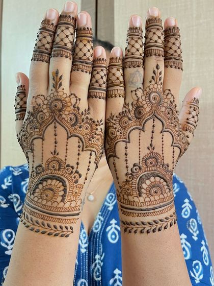 A mirrored image of the guest mehndi, showing both hands held up to display the symmetrical and intricate design.