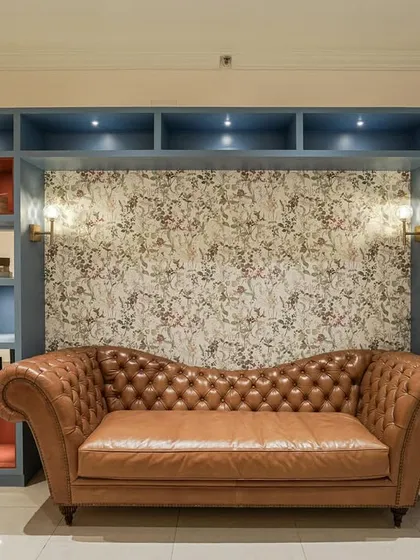 A close-up of the custom bookshelf and tan leather Chesterfield daybed from image 61.