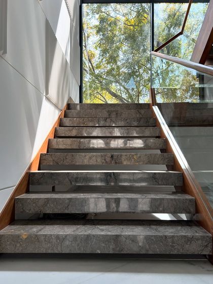 A close-up of the marble steps of the Gulmohar Farmhouse staircase, with sunlight filtering through the open risers and creating beautiful patterns.
