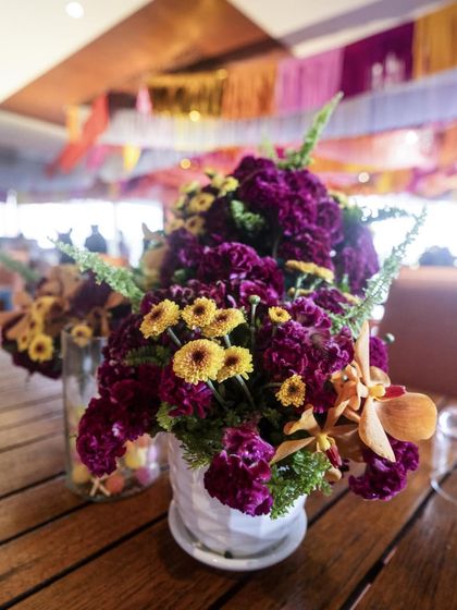 A table centerpiece for the guest dining area, featuring deep purple and yellow chrysanthemums in a simple white vase.