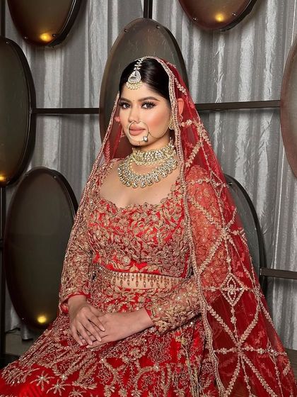 A regal bride in a classic red lehenga, seated with her veil perfectly draped.