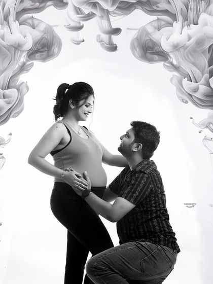A tender moment captured in black and white, with the dad-to-be kneeling to connect with the baby. The creative smoke frame adds a modern, artistic touch to this sweet pose.