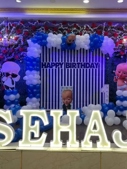 A grand Boss Baby themed birthday stage with large marquee letters, a striped backdrop, and character cutouts.