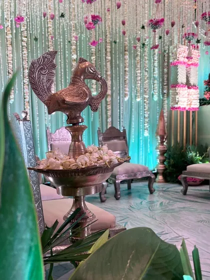 A close-up of a traditional silver peacock lamp, a beautiful element in a sacred ceremony setup. The details honor heritage while contributing to the overall aesthetic.