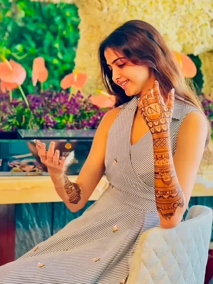 A client admiring her engagement mehndi, which includes her initial 'N' on the back of her hand.